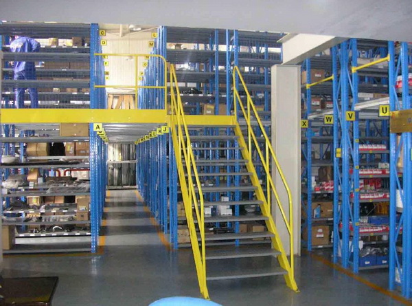 Blue rack-supported mezzanine with yellow safety rails, stairs and shelving below
