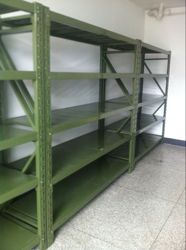 Green industrial shelving with solid shelf levels in a warehouse room