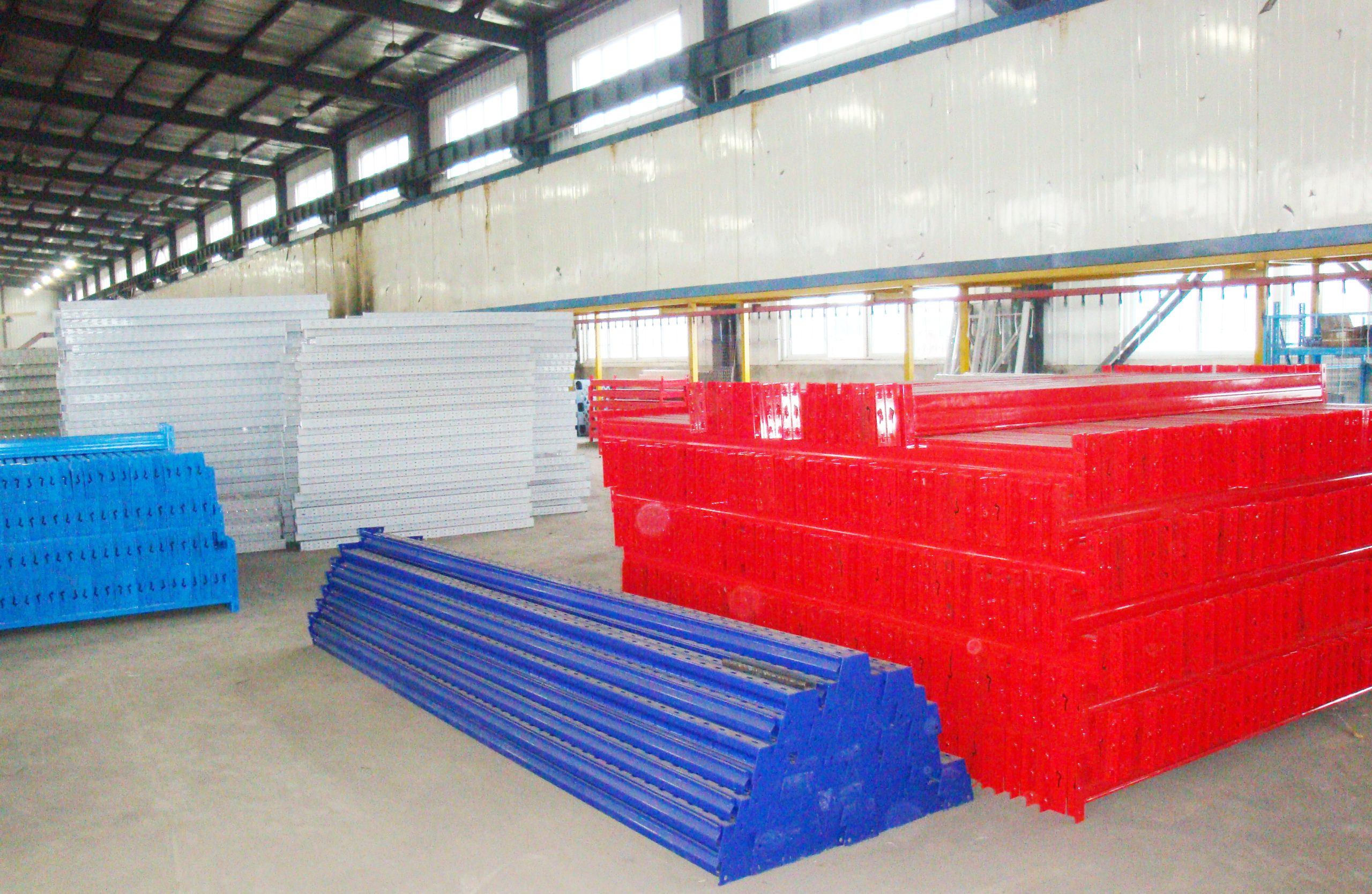 Painted warehouse racking components stored inside the manufacturing workshop